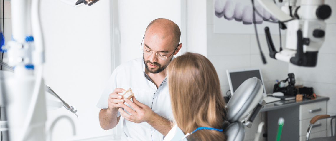 A dentist explains a dental model to a patient in a modern dental clinic.