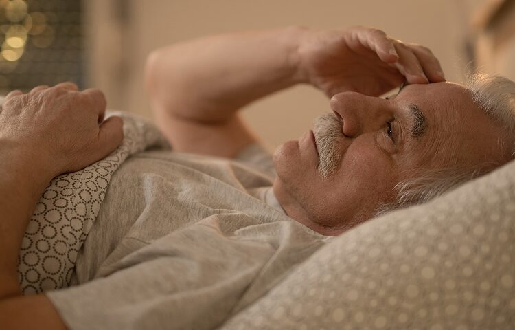 Worried senior man thinking of something while resting in bed at night
